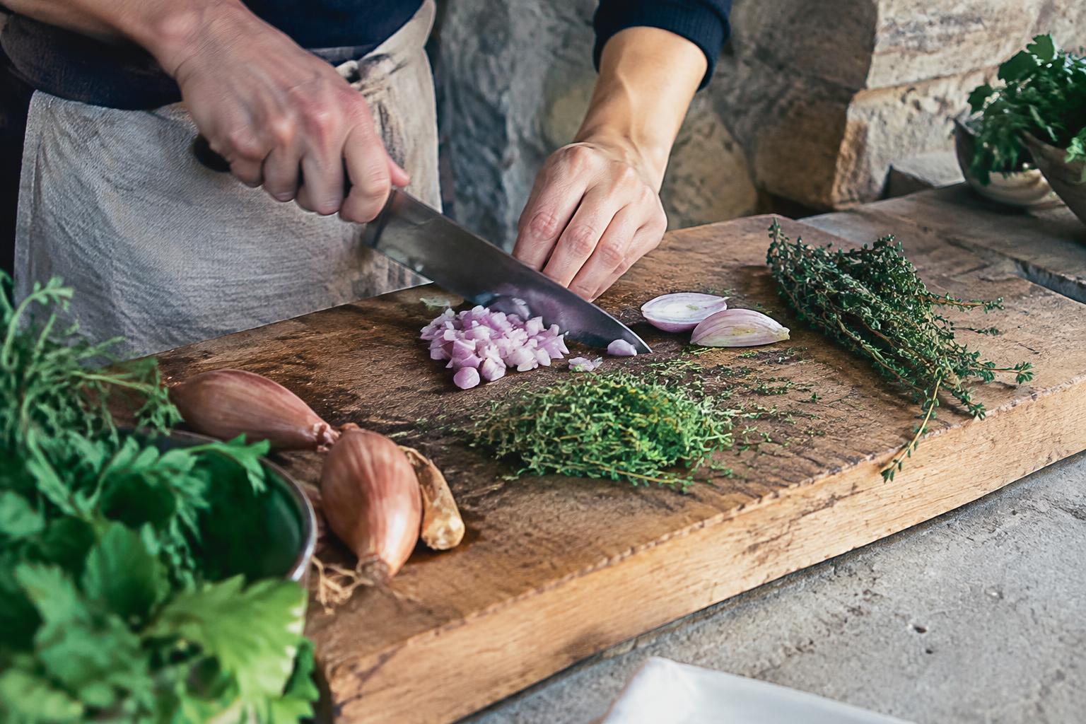 Hands chopping shallots and thyme
